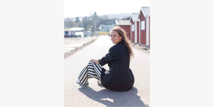 Kvinna sitter på marken och tittar på kameran