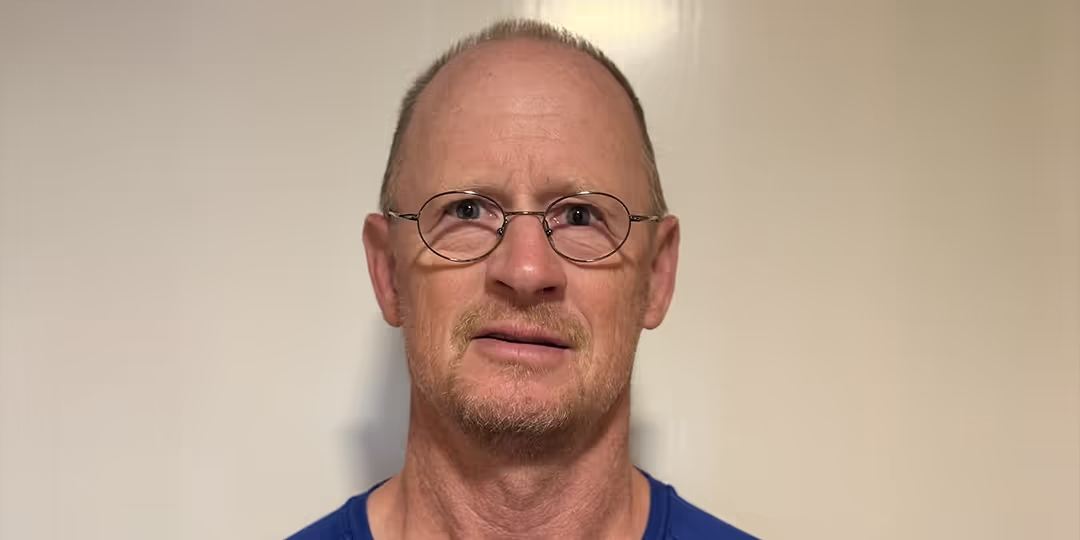 Jonas Fredriksson Medelålders man med glasögon, kort hår och skägg tittar mot kameran. Han bär en blå t-shirt med logotypen "Springtime" och står mot en ljus bakgrund.